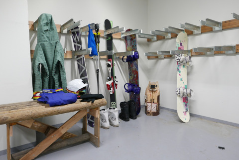 Skirum med jakker, ski, stave, snowboard og udstyr på stativer i Les chalets Huttopia de Bourg-St-Maurice.