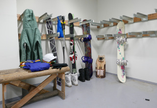 Skirum med jakker, ski, stave, snowboard og udstyr på stativer i Les chalets Huttopia de Bourg-St-Maurice.