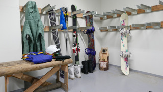 Sala de esquí con chaquetas, esquís, bastones, snowboard y equipo en Les chalets Huttopia de Bourg-St-Maurice.