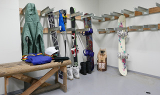 Sala de esquí con chaquetas, esquís, bastones, snowboard y equipo en Les chalets Huttopia de Bourg-St-Maurice.