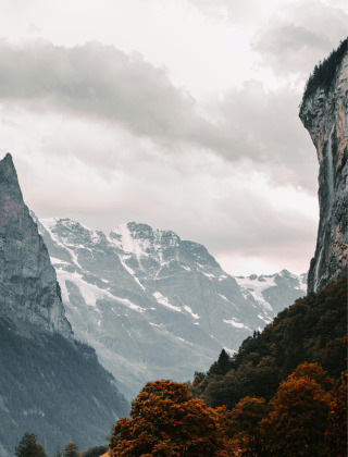 Superbe vue sur un paysage de montagne avec sommets enneigés et arbres à proximité d’un parc de glamping.
