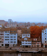Vue du centre historique de Zurich avec maisons colorées, rivière et clocher par temps nuageux.