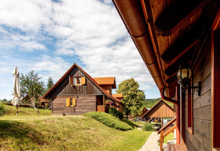 Træhytter med røde tage i Boutique Camping Heart of Nature, Karlovac, Kroatien, under en blå himmel.