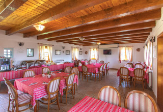 Sala da pranzo con travi in legno e tovaglie rosse al Boutique Camping Heart of Nature di Karlovac, Croazia.