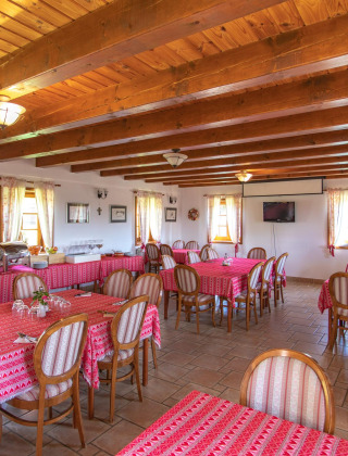 Comedor con vigas de madera y manteles rojos en Boutique Camping Heart of Nature en Karlovac, Croacia.