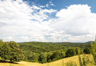Landschap met heuvels en bossen nabij Gorica Lipnička in Karlovac, Kroatië, onder een deels bewolkte hemel.
