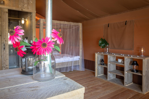 Interno della tenda safari Desert Lodge in Croazia, con arredi in legno, fiori e zanzariera.