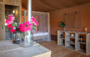 Interior de la tienda safari Desert Lodge en Croacia, muebles de madera, flores y mosquitera.