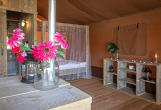 Interior de la tienda safari Desert Lodge en Croacia, muebles de madera, flores y mosquitera.