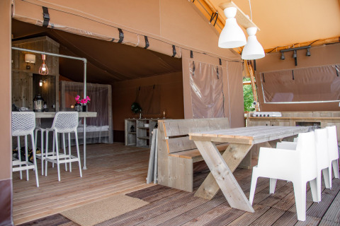 Interno della tenda safari Desert Lodge con mobili in legno e zona pranzo presso Heart of Nature in Croazia.