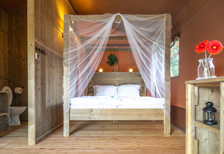 Interior de la tienda safari Desert Lodge en Boutique Camping Heart of Nature en Croacia, con cama de madera.