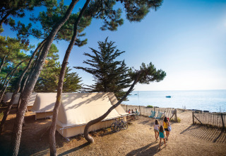 Familiekamperen aan het strand met tenten en zeezicht op Huttopia Noirmoutier in Frankrijk.