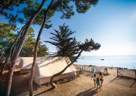 Familiekamperen aan het strand met tenten en zeezicht op Huttopia Noirmoutier in Frankrijk.