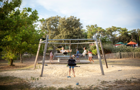Niños jugando en columpios en el parque infantil de Huttopia Noirmoutier, Pays de la Loire, Francia.