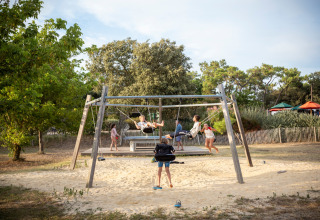 Kinderen spelen op een schommel in Huttopia Noirmoutier vakantiepark, Pays de la Loire, Frankrijk.