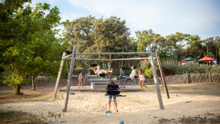 Kinder schaukeln und spielen auf dem Spielplatz im Ferienpark Huttopia Noirmoutier, Pays de la Loire, Frankreich.