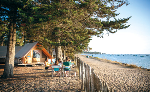Gezin kampeert aan het strand bij Huttopia Noirmoutier, omringd door bomen in Pays de la Loire, Frankrijk.