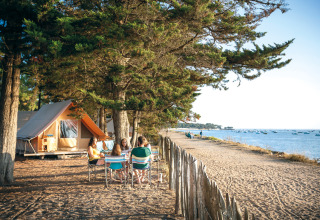 Famiglia si gode il campeggio fronte mare vicino alla tenda a Huttopia Noirmoutier, Pays de la Loire, Francia.