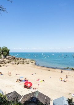 Strandbild vom Huttopia Noirmoutier in Pays de la Loire, Frankreich, mit Leuten und Booten am Wasser.