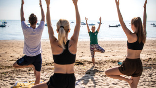 Gäste des Ferienparks machen Yoga am Strand von Huttopia Noirmoutier, Pays de la Loire, Frankreich.