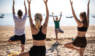 Turistas disfrutando de una sesión de yoga en la playa en Huttopia Noirmoutier, Pays de la Loire, Francia.
