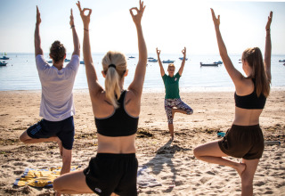 Ospiti del villaggio turistico fanno yoga sulla spiaggia a Huttopia Noirmoutier, Pays de la Loire, Francia.