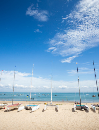 Boote mit Masten stehen am Sandstrand in der Nähe von Noirmoutier en l'île, Pays de la Loire, Frankreich.