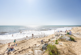 Folk nyder en solrig dag på stranden nær Ars-en-Ré, Nouvelle-Aquitaine, Frankrig, med udsigt til havet.