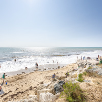 Personas disfrutan de un día soleado en la playa cerca de Ars-en-Ré, Nueva Aquitania, Francia, junto al mar.