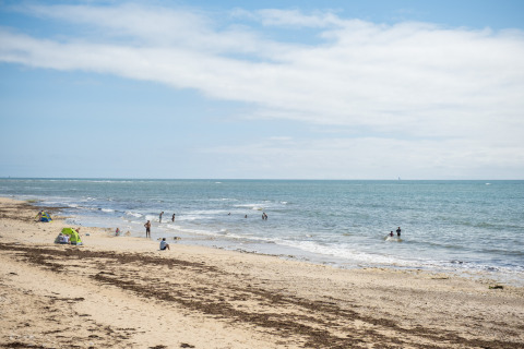 Strand in der Nähe von Ars-en-Ré, Nouvelle-Aquitaine, Frankreich, mit wenigen Badegästen und ruhigem Meer.