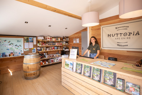 Recepción del parque vacacional Huttopia Ars-en-Ré en Nouvelle-Aquitaine, Francia, con productos locales y personal.