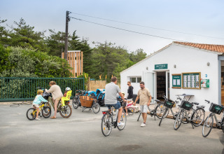 Familier cykler og samles foran en bygning i ferieparken Huttopia Ars-en-Ré, Nouvelle-Aquitaine, Frankrig.