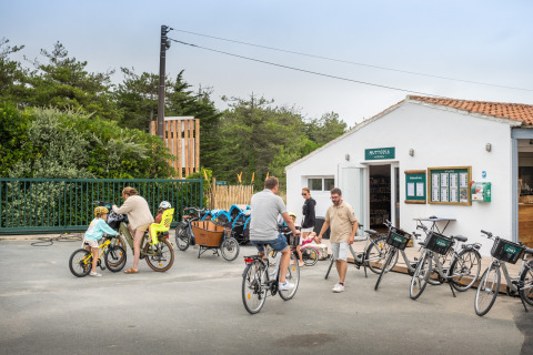 Familias montan en bicicleta y se reúnen frente a un edificio en Huttopia Ars-en-Ré, Nouvelle-Aquitaine, Francia.