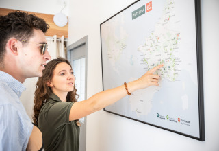 Two people looking at a map at Huttopia Ars-en-Ré holiday park in Nouvelle-Aquitaine, France.