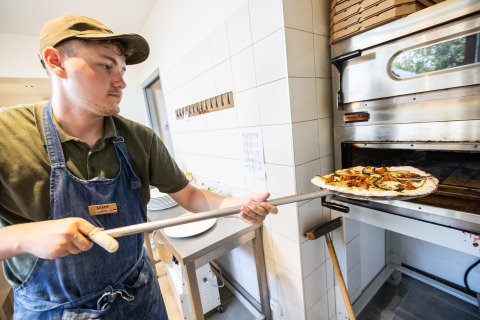 Un empleado de Huttopia Ars-en-Ré mete una pizza en el horno en el parque vacacional de Nouvelle-Aquitaine.