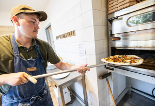 En medarbejder på Huttopia Ars-en-Ré laver pizza i stenovn på feriepark i Nouvelle-Aquitaine, Frankrig.