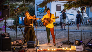 Músicos actúan al aire libre en el parque vacacional Huttopia Ars-en-Ré en Nouvelle-Aquitaine, Francia, de noche.