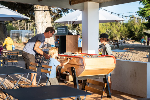 Family plays foosball outside at Huttopia Ars-en-Ré holiday park in Nouvelle-Aquitaine, France.