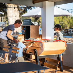 Familia juega futbolín al aire libre en el parque vacacional Huttopia Ars-en-Ré en Nouvelle-Aquitaine, Francia.