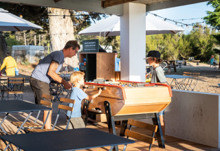 Family plays foosball outside at Huttopia Ars-en-Ré holiday park in Nouvelle-Aquitaine, France.