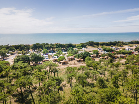 Vista aérea del parque vacacional Huttopia Ars-en-Ré en Nouvelle-Aquitaine, Francia, con cabañas y mar.