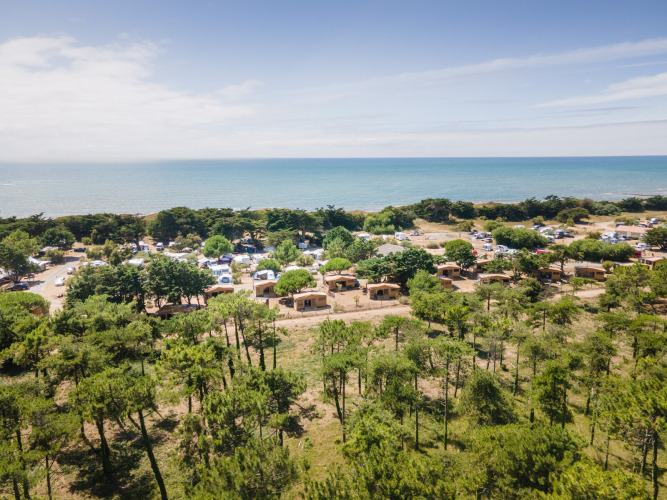 Aerial view of Huttopia Ars-en-Ré holiday park in Nouvelle-Aquitaine, France, with cottages by the sea.