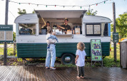 Una mujer con dos niños pide comida en un food truck vintage en el parque vacacional Huttopia Calvados, Normandía.