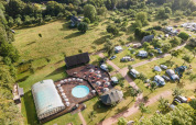 Luftfoto af ferieparken Huttopia Calvados - Normandie med swimmingpool, telte og grøn natur.