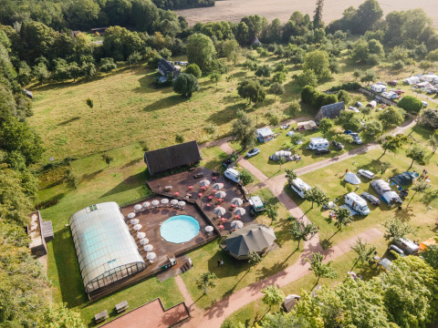 Luftfoto af ferieparken Huttopia Calvados - Normandie med swimmingpool, telte og grøn natur.