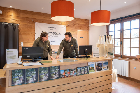 Receptionen på Huttopia Calvados - Normandie med to medarbejdere i samtale bag disken i Frankrig.