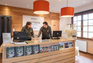 Receptionen på Huttopia Calvados - Normandie med to medarbejdere i samtale bag disken i Frankrig.