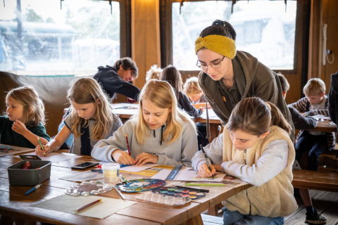 Niños realizan actividades creativas bajo la supervisión de un adulto en Huttopia Calvados, Normandía, Francia.