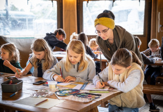 Kinderen doen creatieve activiteiten onder begeleiding van een volwassene bij Huttopia Calvados in Normandië, Frankrijk.