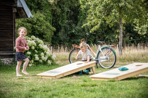 Dos niños juegan a un juego de jardín cerca de una bicicleta en Huttopia Calvados, Normandía, Francia.